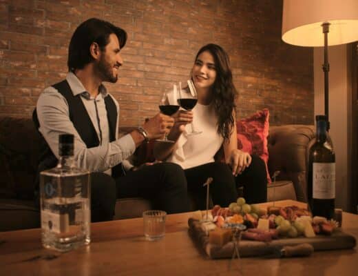 a man and a woman sitting on a couch holding wine glasses