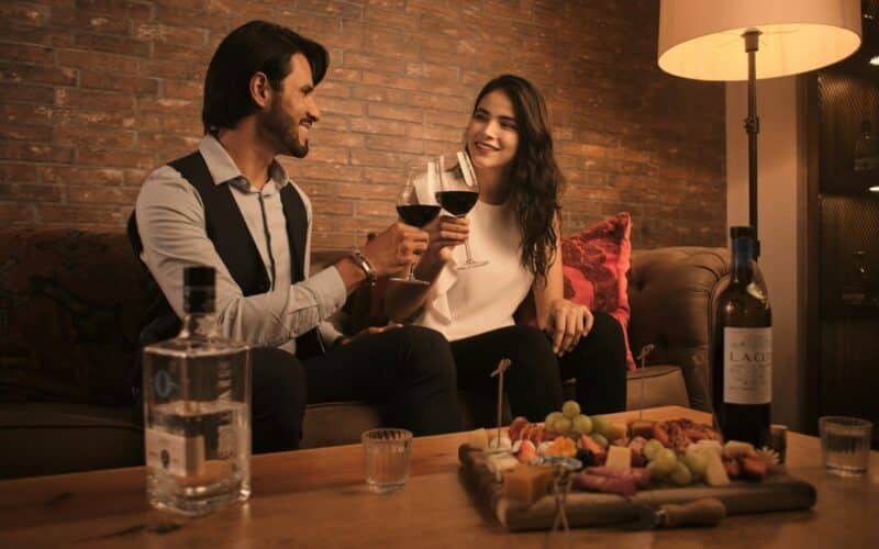 a man and a woman sitting on a couch holding wine glasses